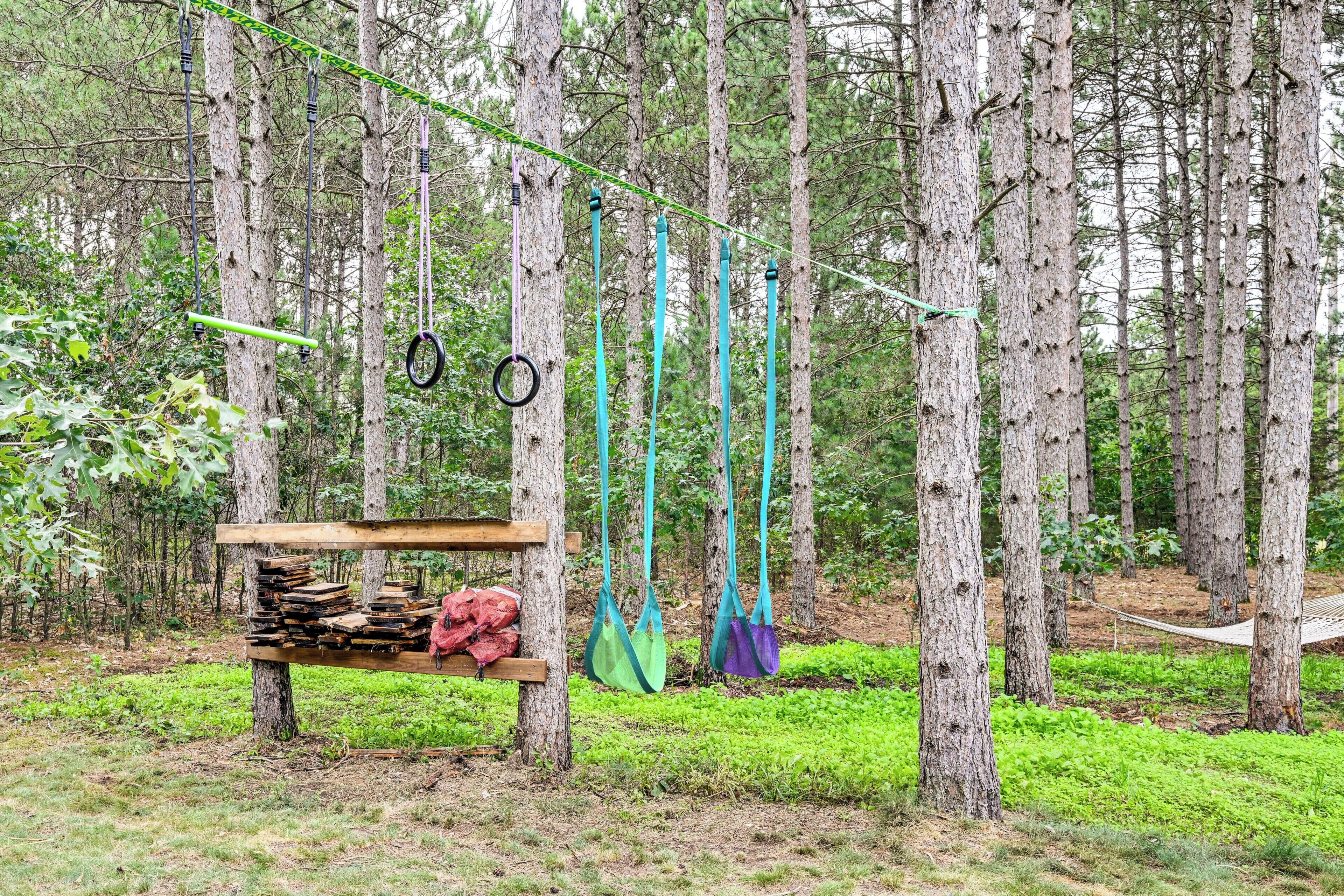 A forested area with a wooden structure, ropes, and bags.