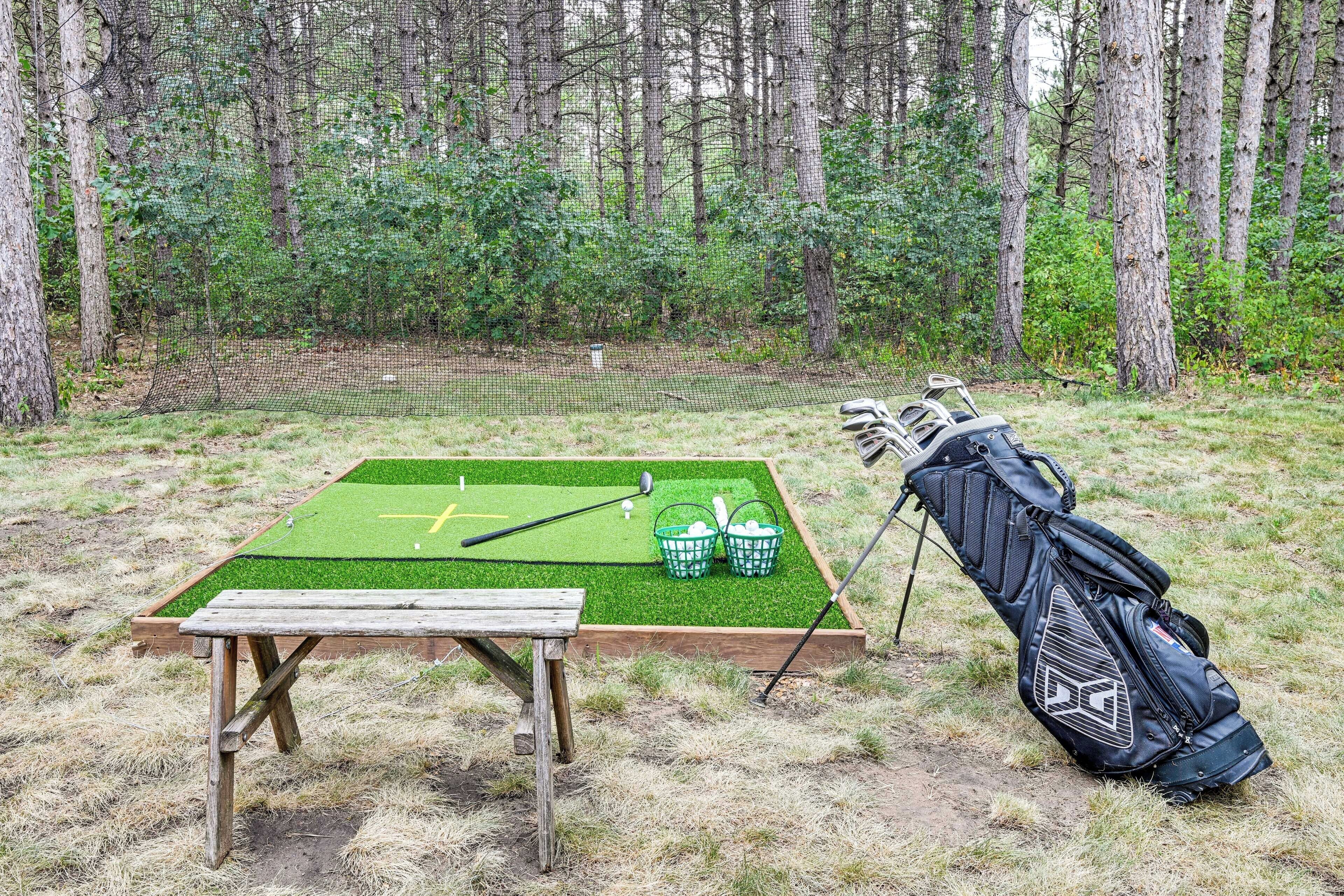 A golf practice area with a netted enclosure, a wooden table, and a golf bag with clubs.
