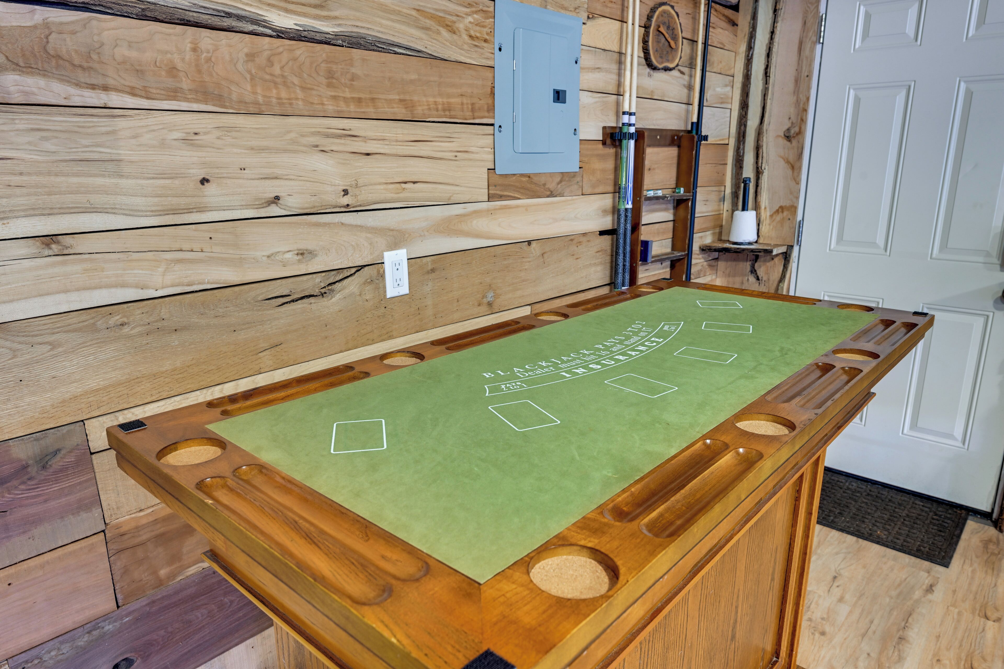 A wooden table with a green felt surface, a power outlet, and a wooden wall with a light switch.