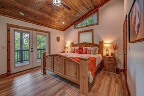 Un dormitorio con estructura de madera, una cama, lámparas de noche y una decoración de cabeza de oso en la pared.