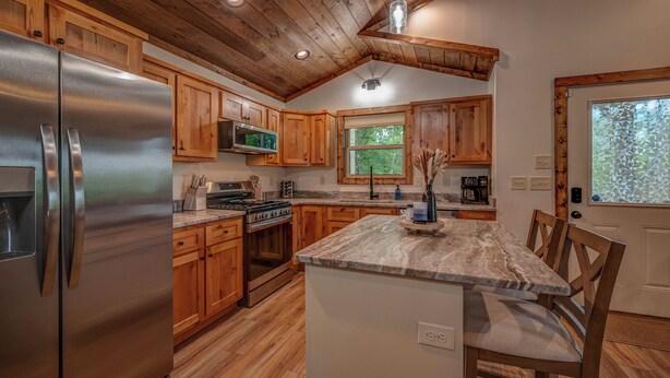 A kitchen with wooden cabinets, a stainless steel refrigerator, a microwave, and a stove. - Blue Ridge Views, Hot Tub! Murphy Mtn Cabin (Murphy)