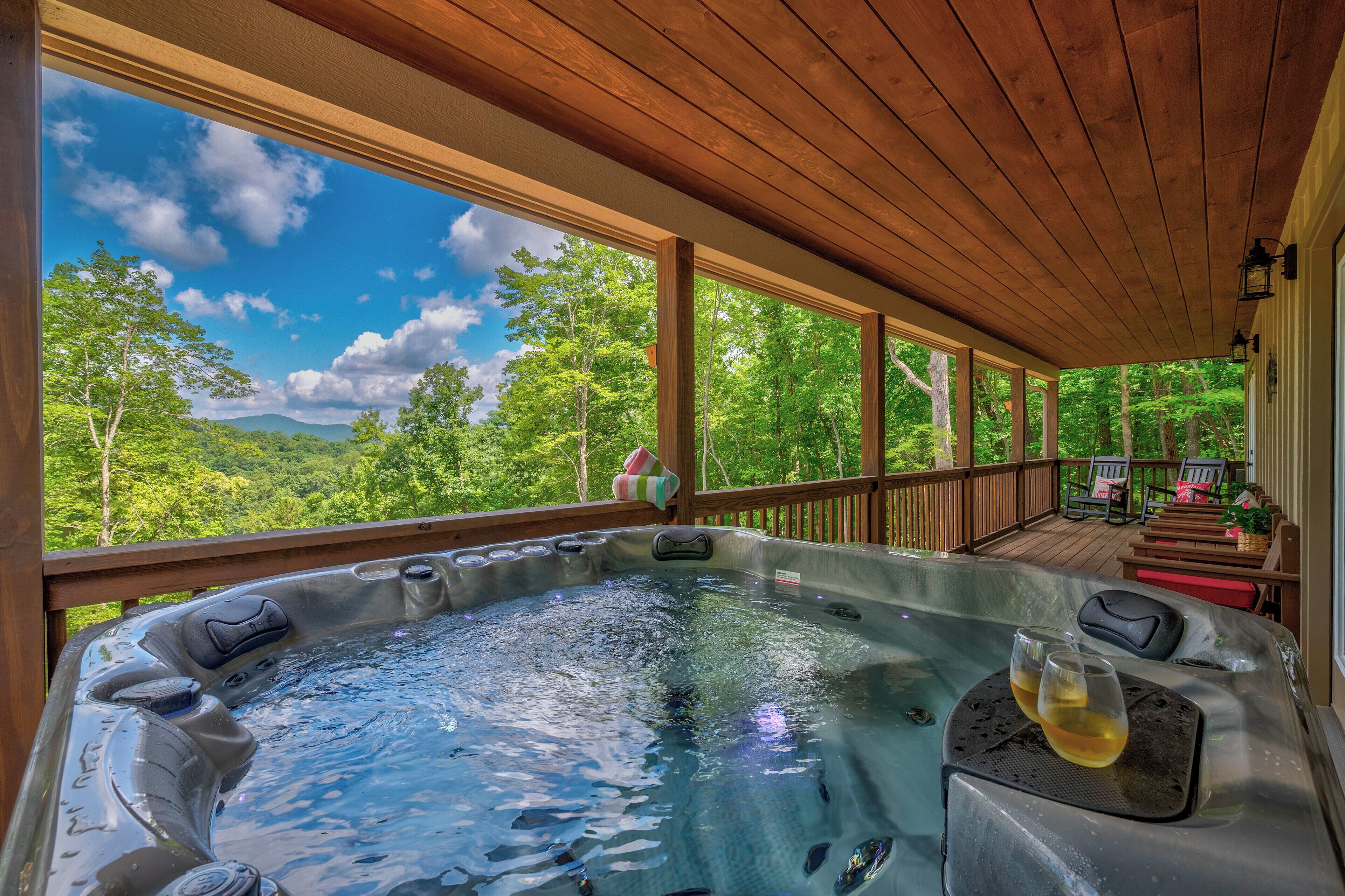 Ein Whirlpool auf einer Holzterrasse mit Blick auf Wald und Berge.