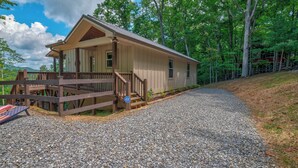 A single-story cabin with a porch, a gravel driveway, and a forested backdrop. - Blue Ridge Views, Hot Tub! Murphy Mtn Cabin (Murphy)