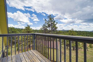 Eine Holzterrasse mit Blick auf einen Wald und Berge.