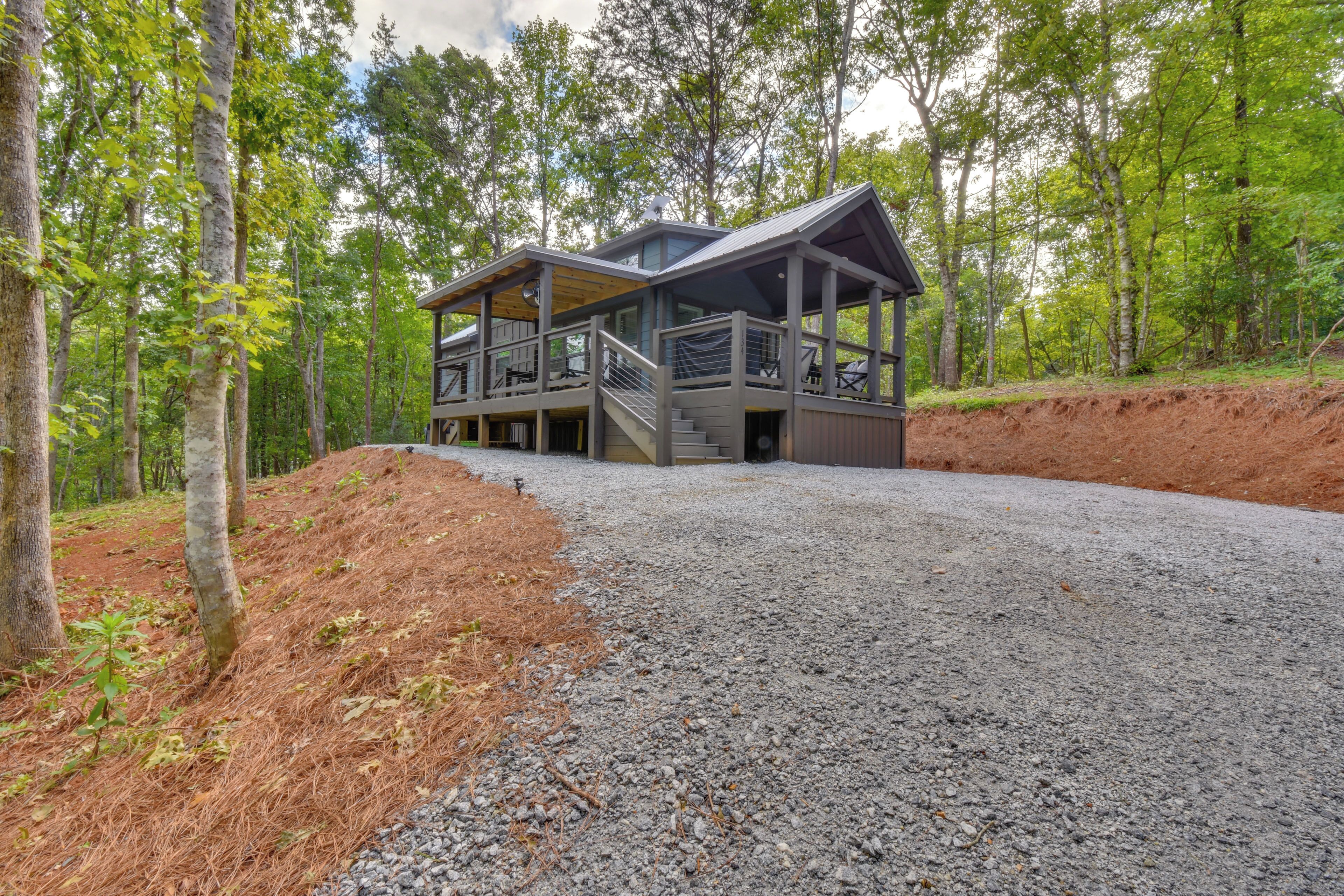 A cabin with a covered deck and a staircase leading to a second floor.