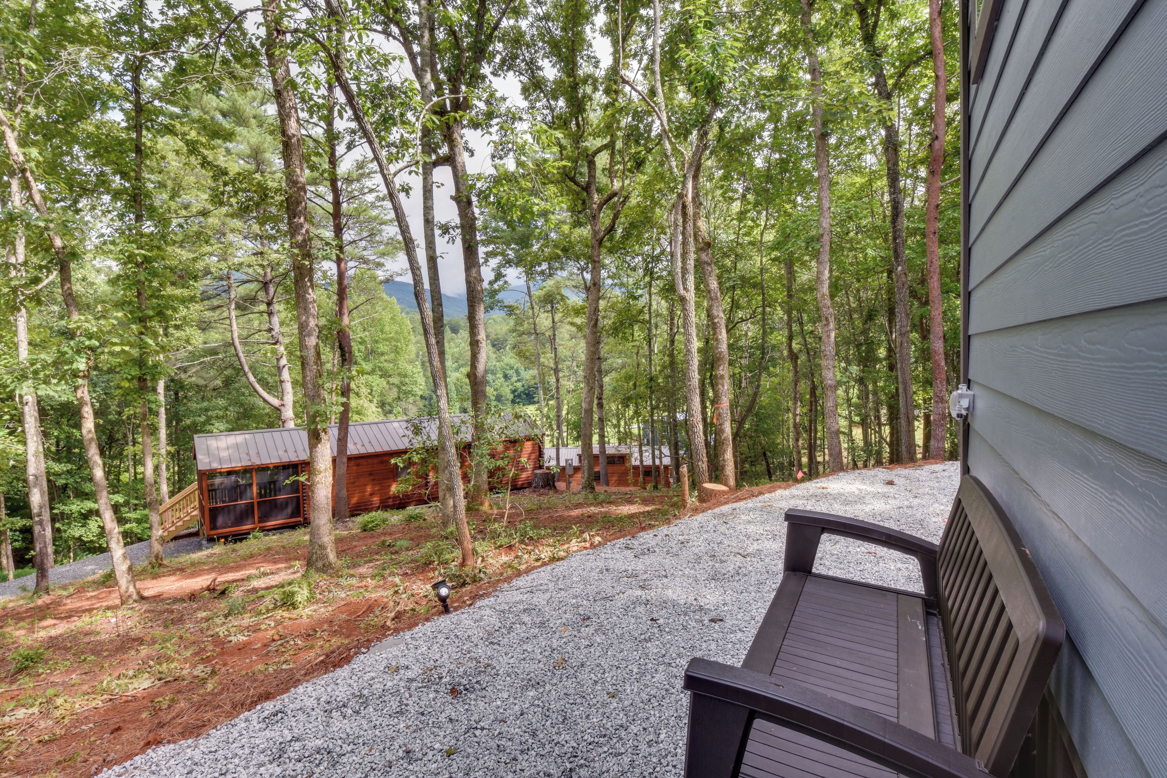 Eine Holzterrasse mit einem Kiesweg, der zu einer Holzhütte im Wald führt.