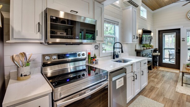 A modern kitchen with stainless steel appliances, a built-in oven, and a dishwasher. - Tiny Home - Fire Pit, Grill, Deck & View! (Otto)