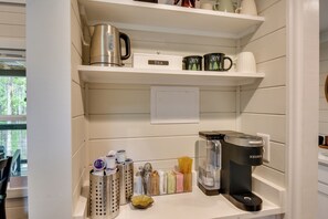 Eine Küche mit Kaffeemaschine, Wasserkocher und verschiedenen Küchenutensilien in Regalen.