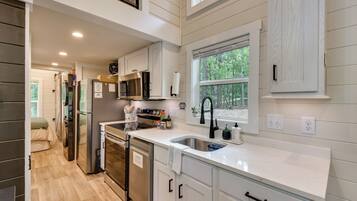 A modern kitchen with stainless steel appliances, a built-in oven, and a window with a view of the outdoors.