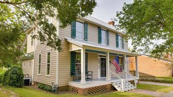 A two-story house with a porch, a brick foundation, and an American flag.