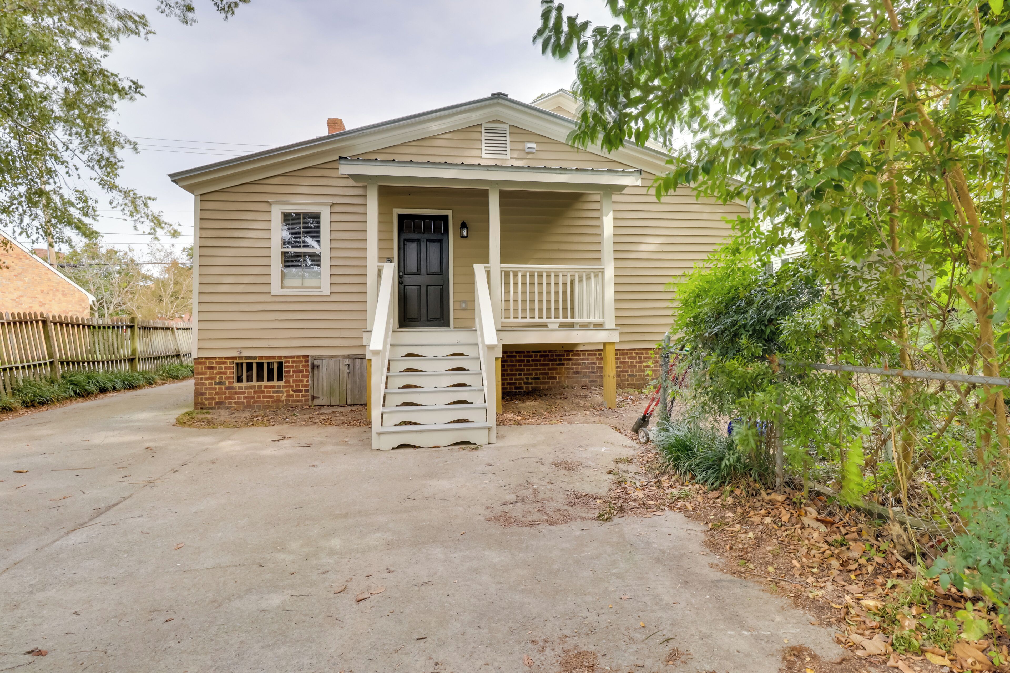 A single-story house with a front porch, a small staircase leading to the door, and a brick foundation.