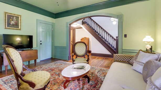 A living room with a sofa, armchair, TV, and a patterned rug.
