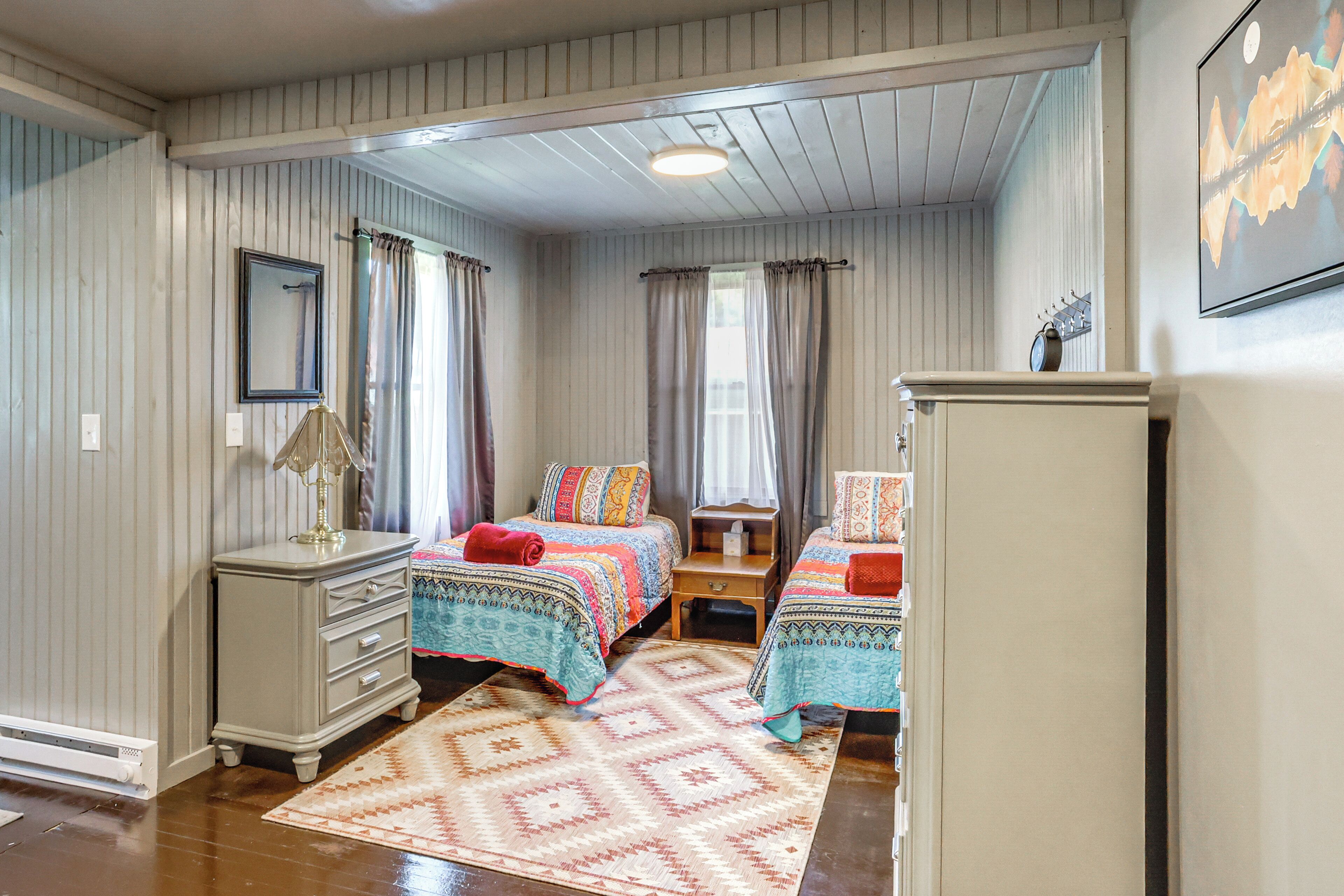 A bedroom with two beds, a dresser, a nightstand, and a mirror.