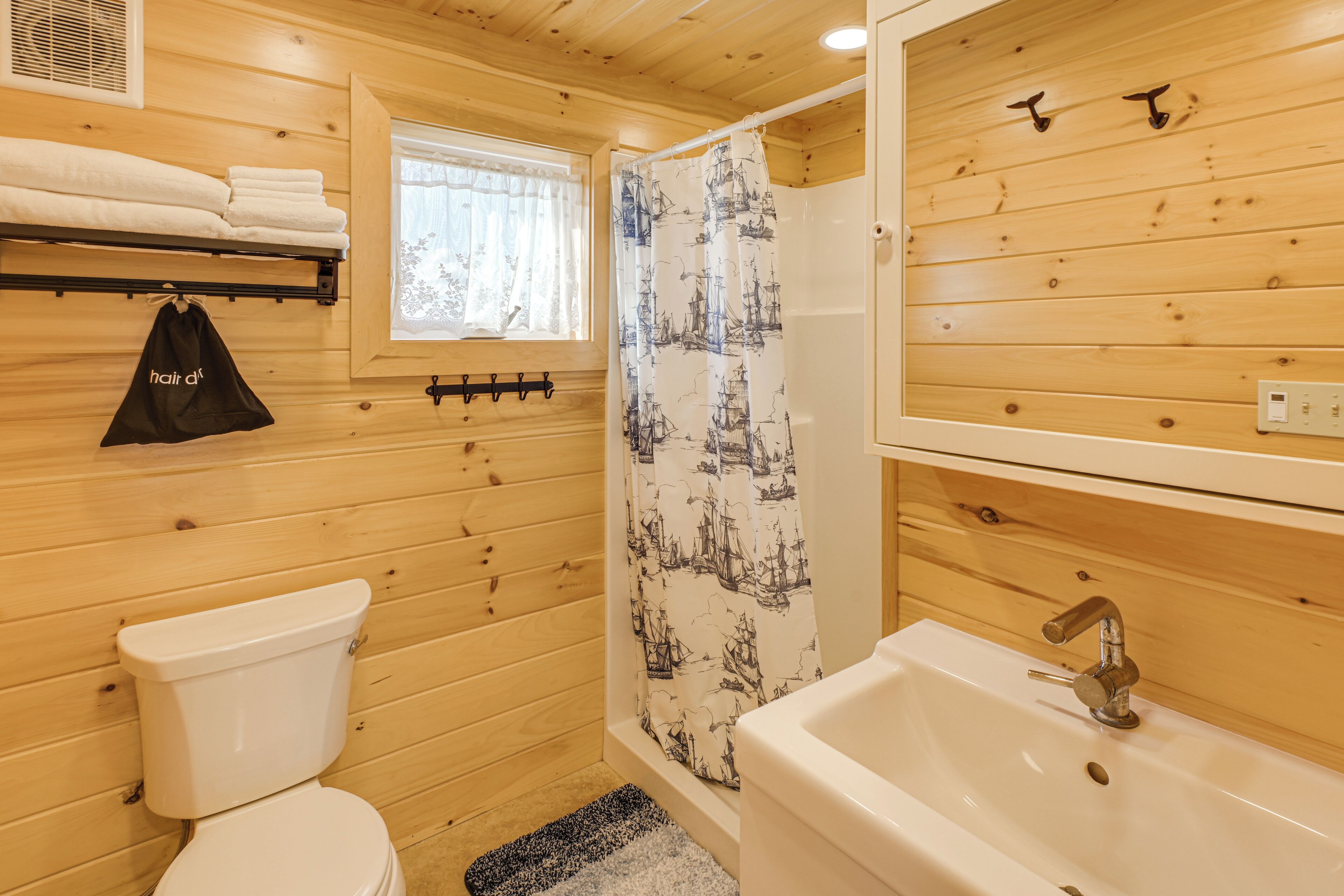 A wooden interior bathroom with a toilet, sink, and shower curtain.