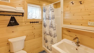 A wooden interior bathroom with a toilet, sink, and shower curtain.