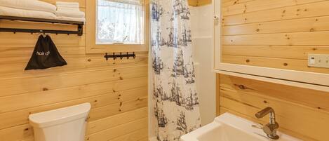 A wooden interior bathroom with a toilet, sink, and shower curtain.