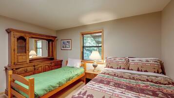 A bedroom with a wooden bed, a nightstand, a dresser, a window, and a lamp.