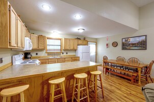 Una cocina con armarios de madera, un refrigerador blanco, una estufa y un comedor con una mesa y sillas de madera.
