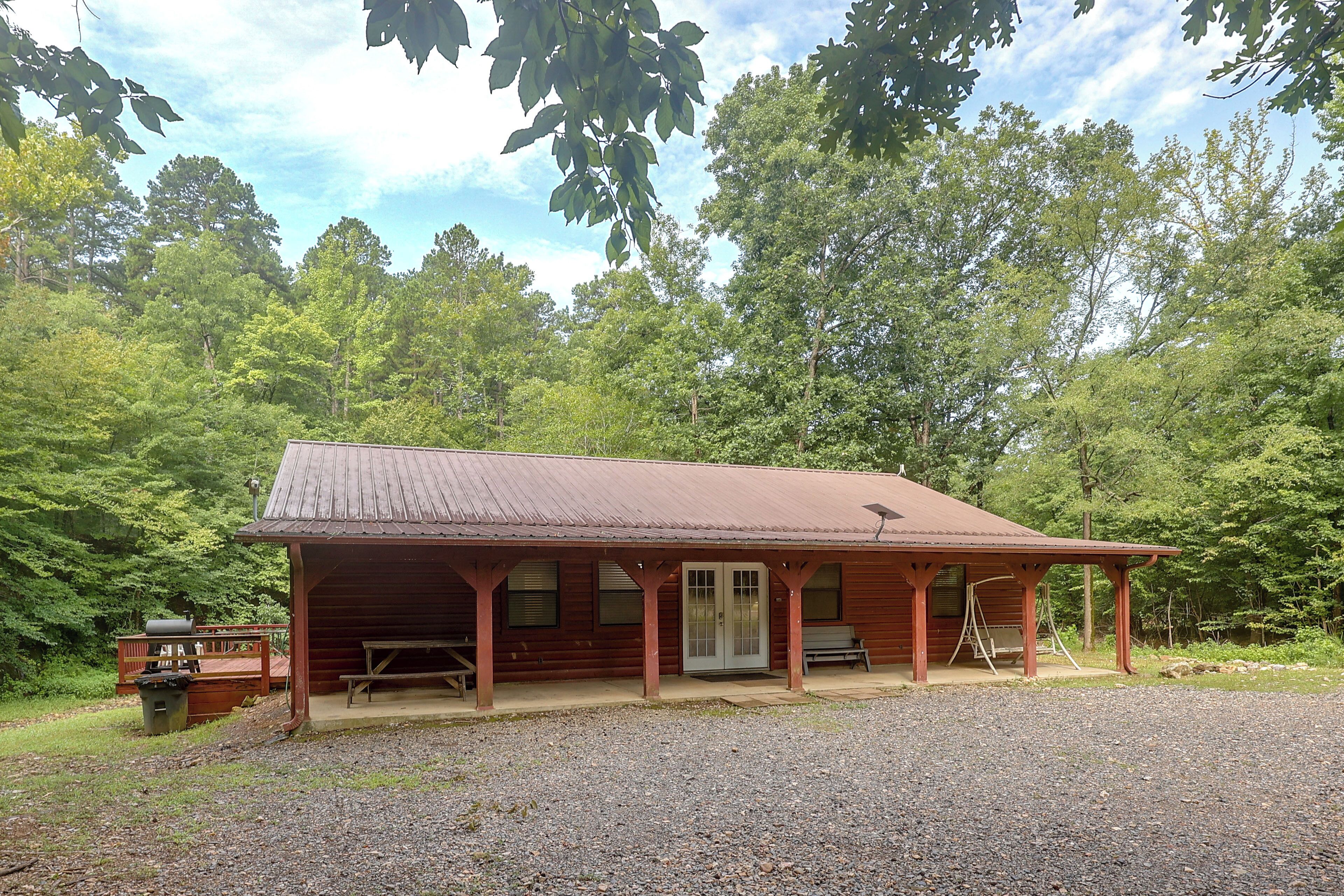 A rustic cabin with a porch, a picnic table, and a bench.