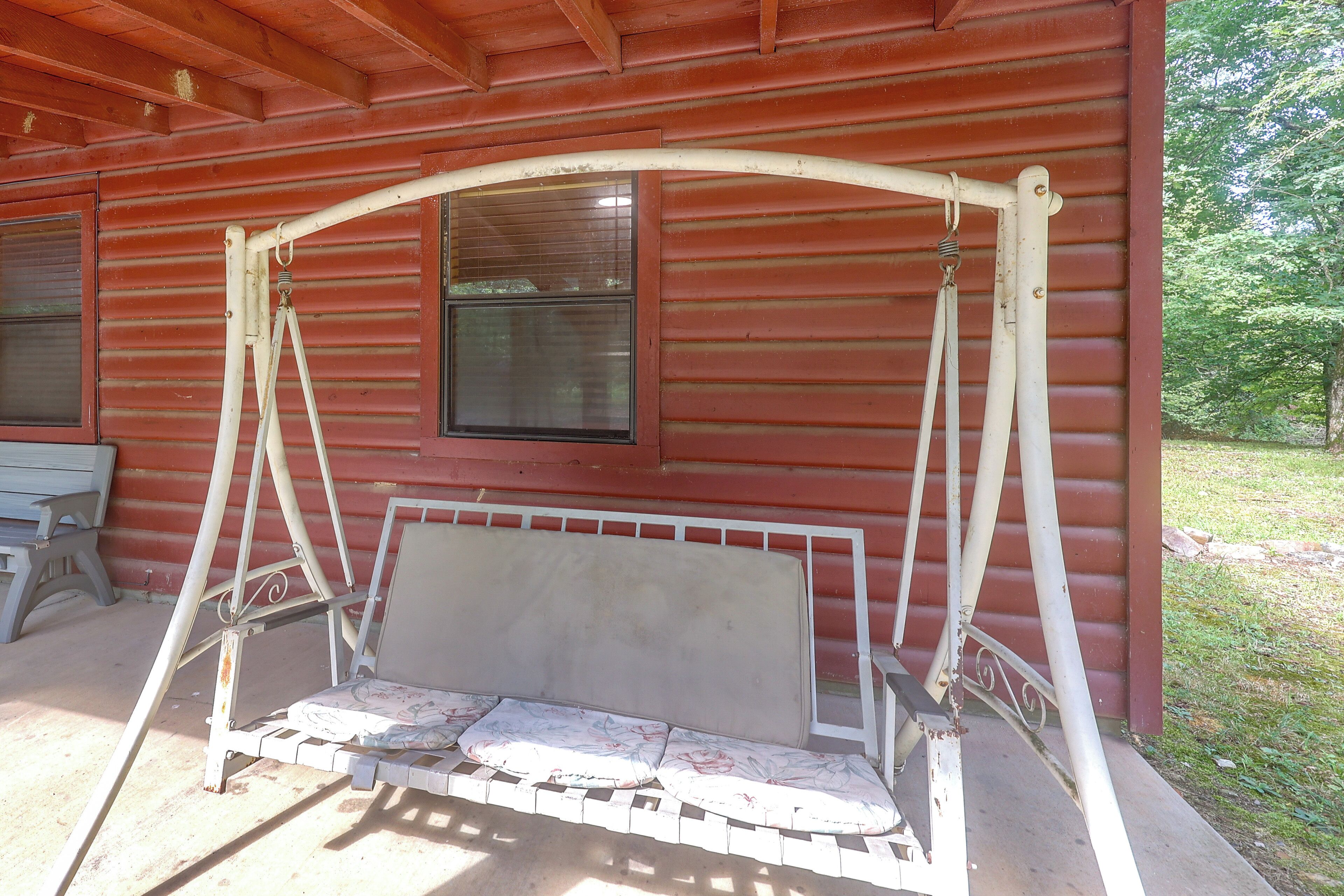 Une véranda avec une balançoire, une fenêtre et un banc.