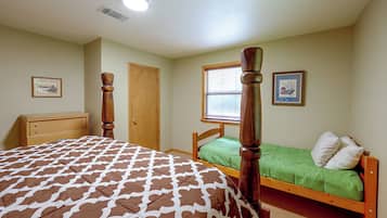 A bedroom with a four-poster bed, a single bed, a dresser, and a window with blinds.