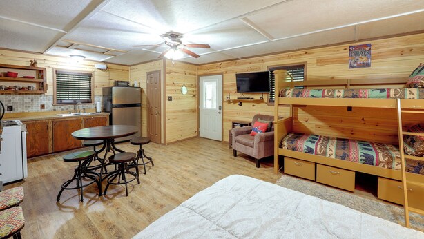 A compact cabin with a kitchenette, a dining area, a single bed, and a bunk bed.