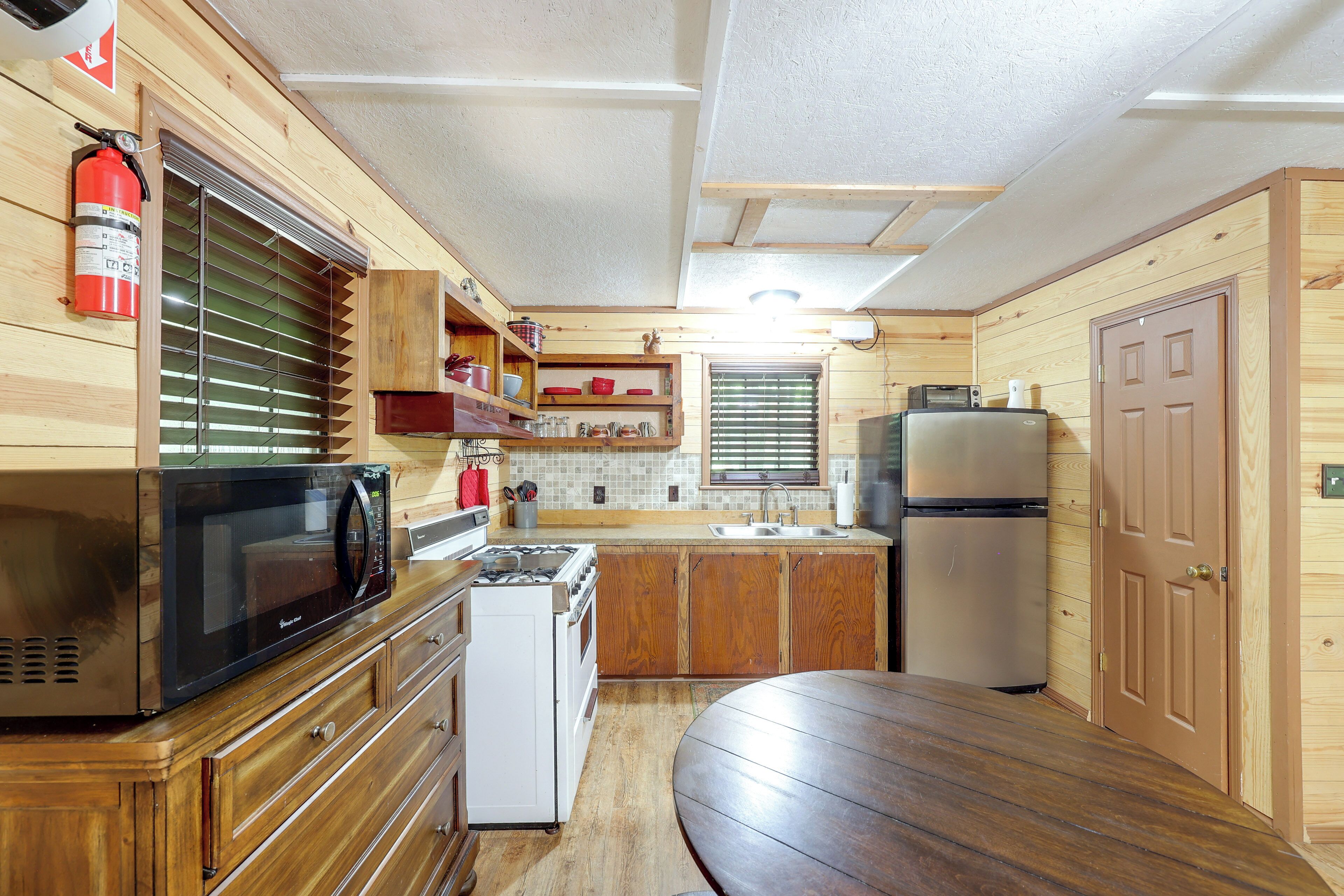 A compact kitchen with a microwave, stove, sink, and refrigerator.