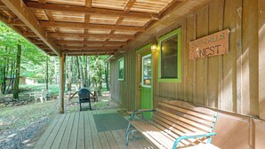 A wooden cabin with a covered porch, a sign reading 'SQUIRRELS NEST,' and a bench.