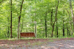 A swing set in a forested area with a gravel path.