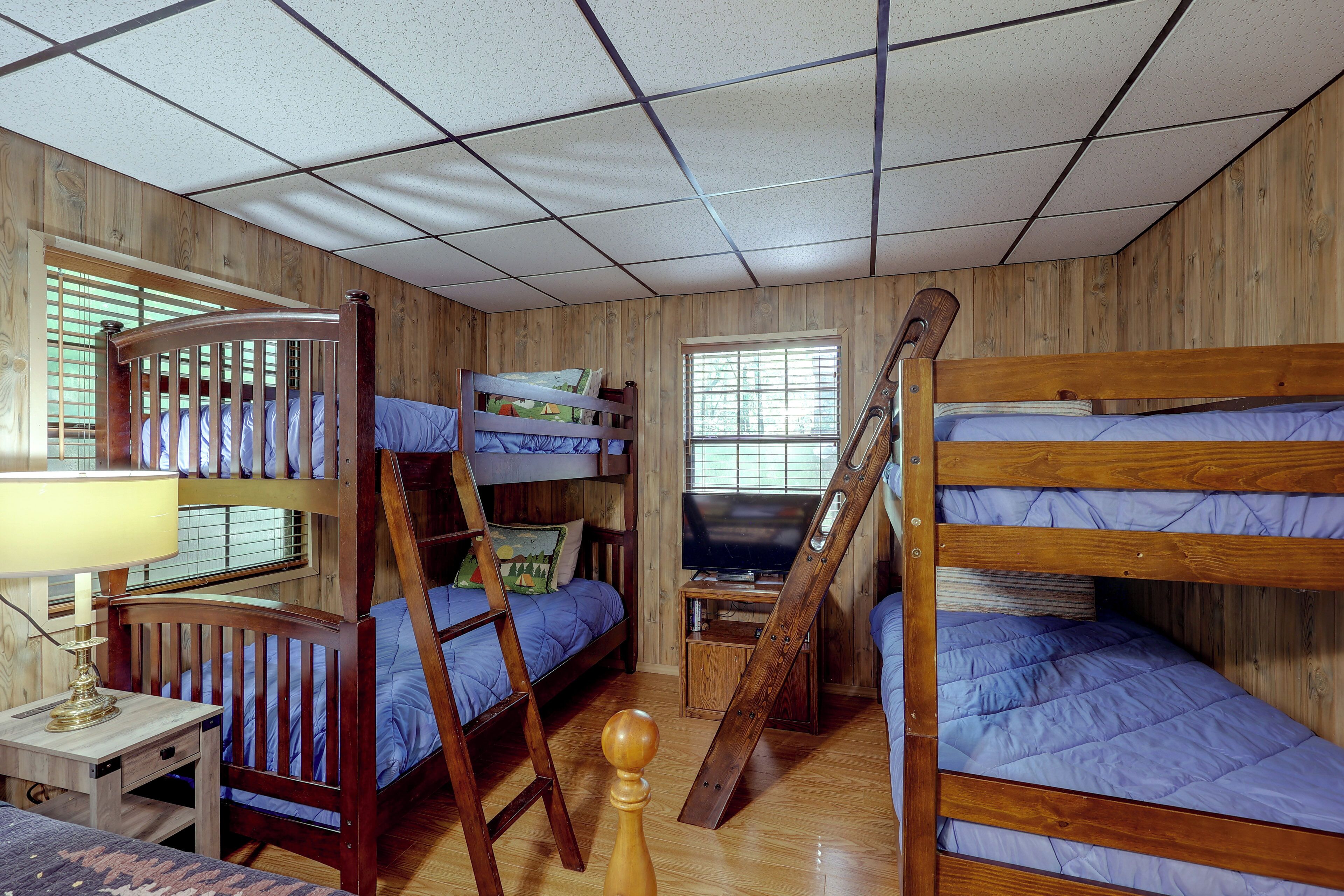 A bunk bed room with a television, a desk, and a window.