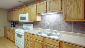 A kitchen with wooden cabinets, a white stove, a microwave, and a stainless steel sink.
