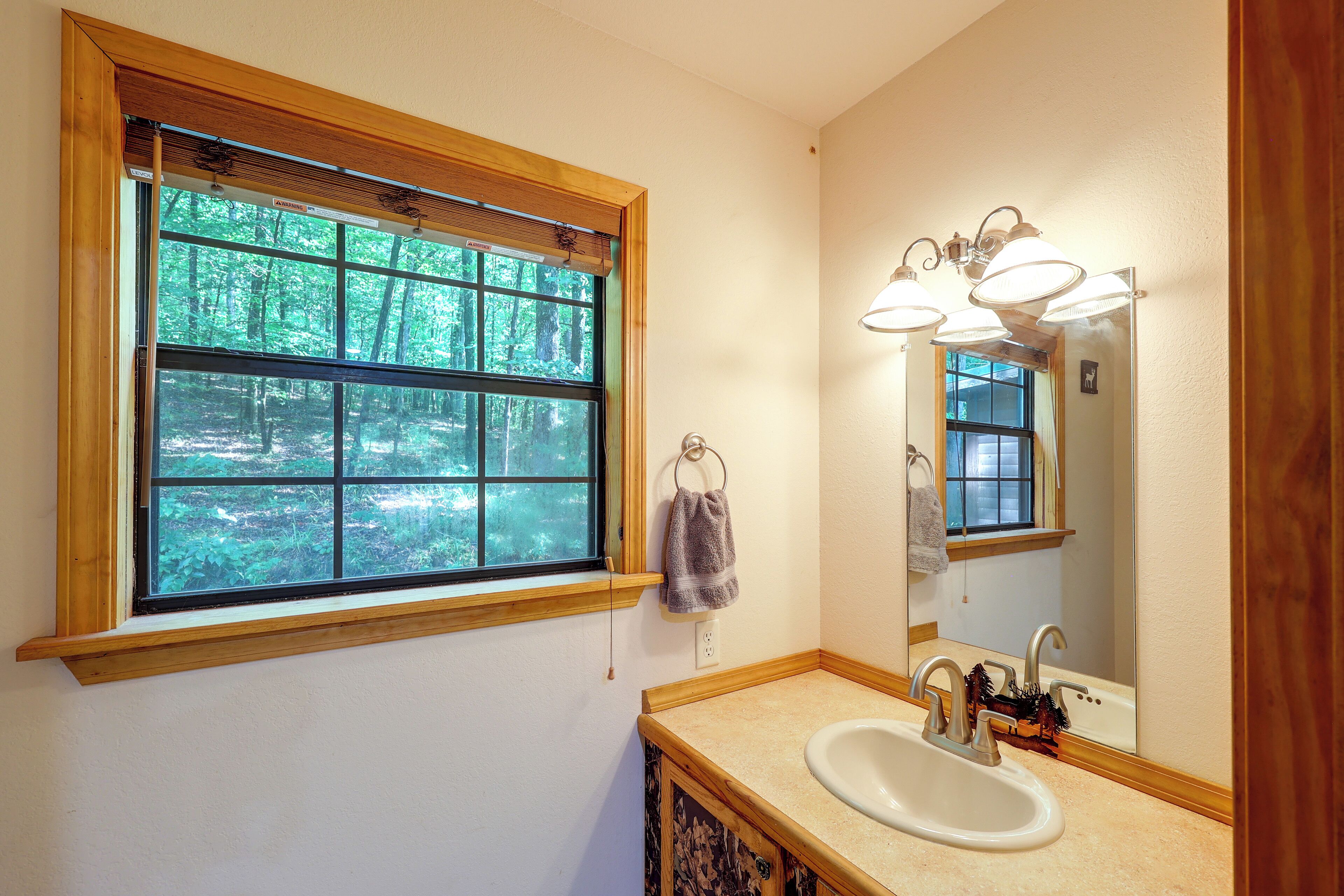 A bathroom with a window, a sink, and a mirror.