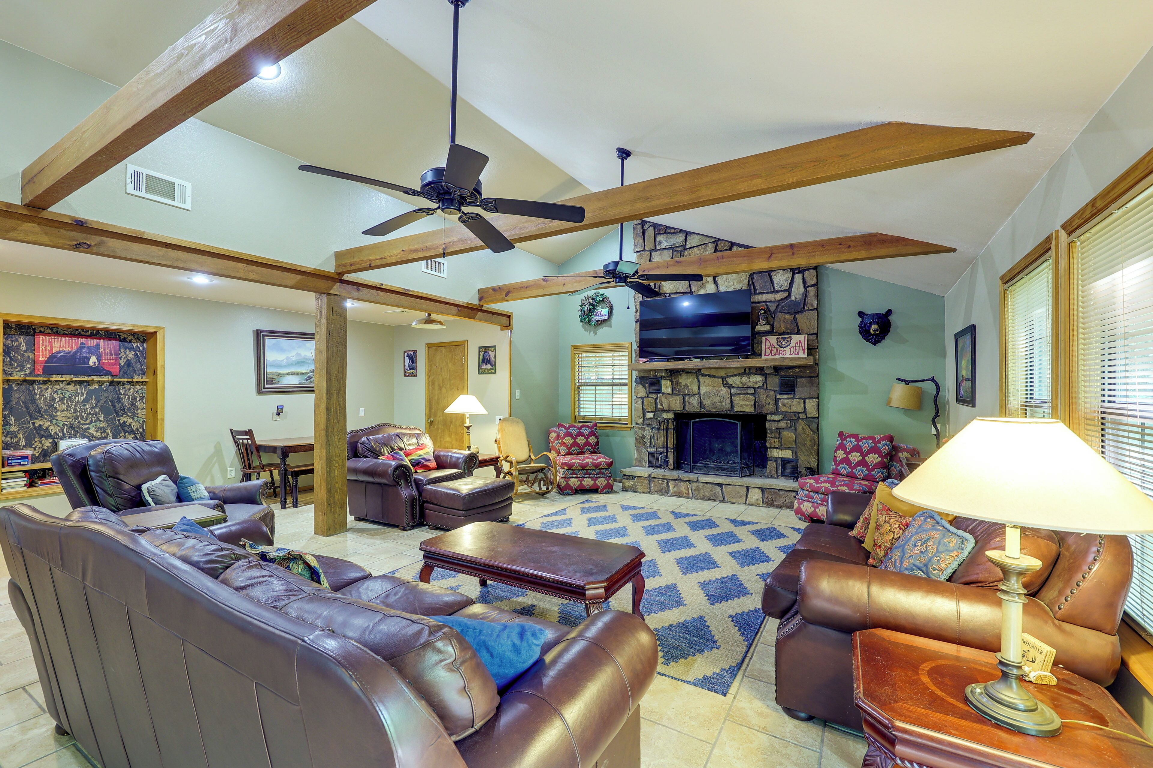 A spacious living room with leather sofas, a fireplace, and a ceiling fan.