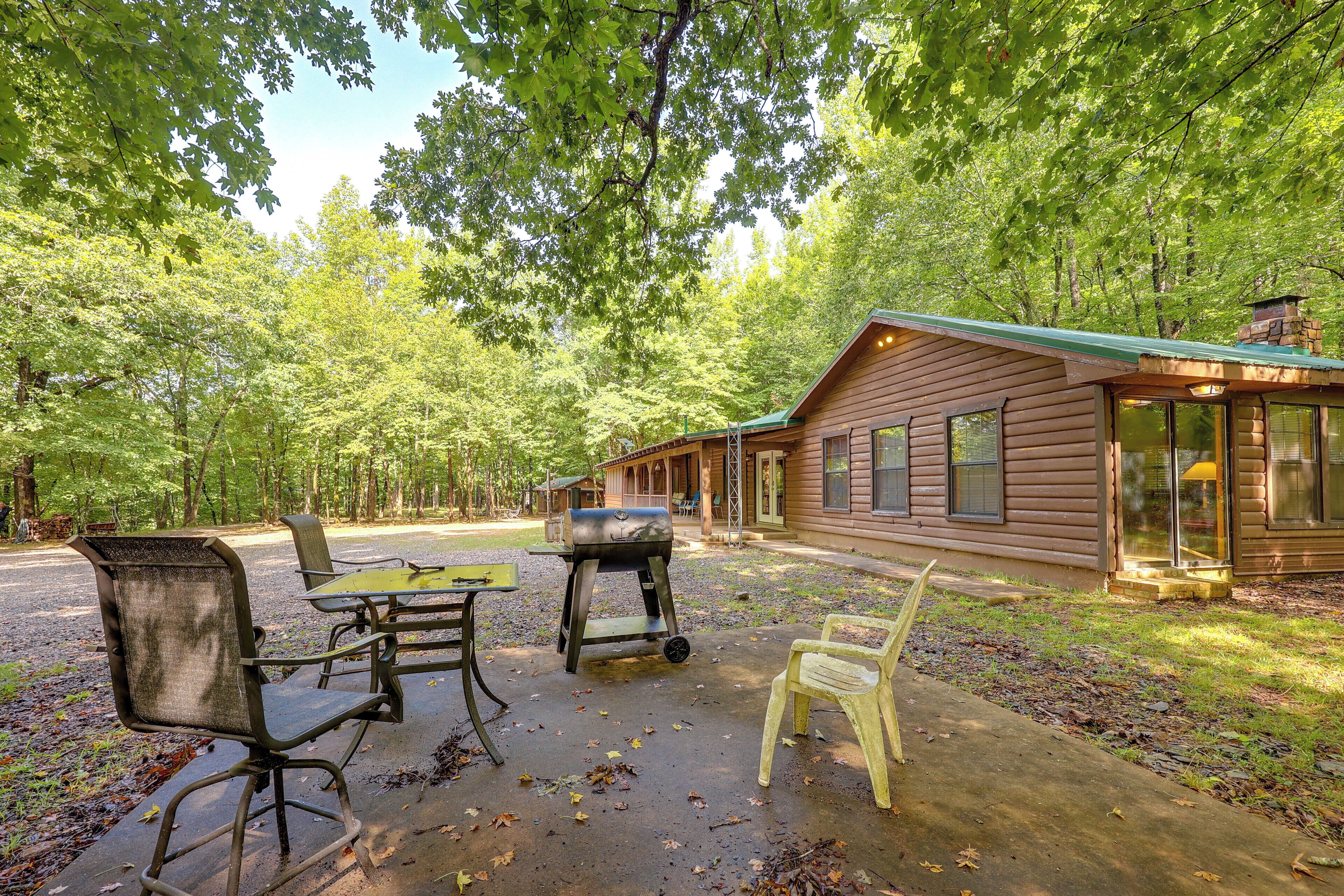 A rustic cabin with a patio area, outdoor seating, and a grill.