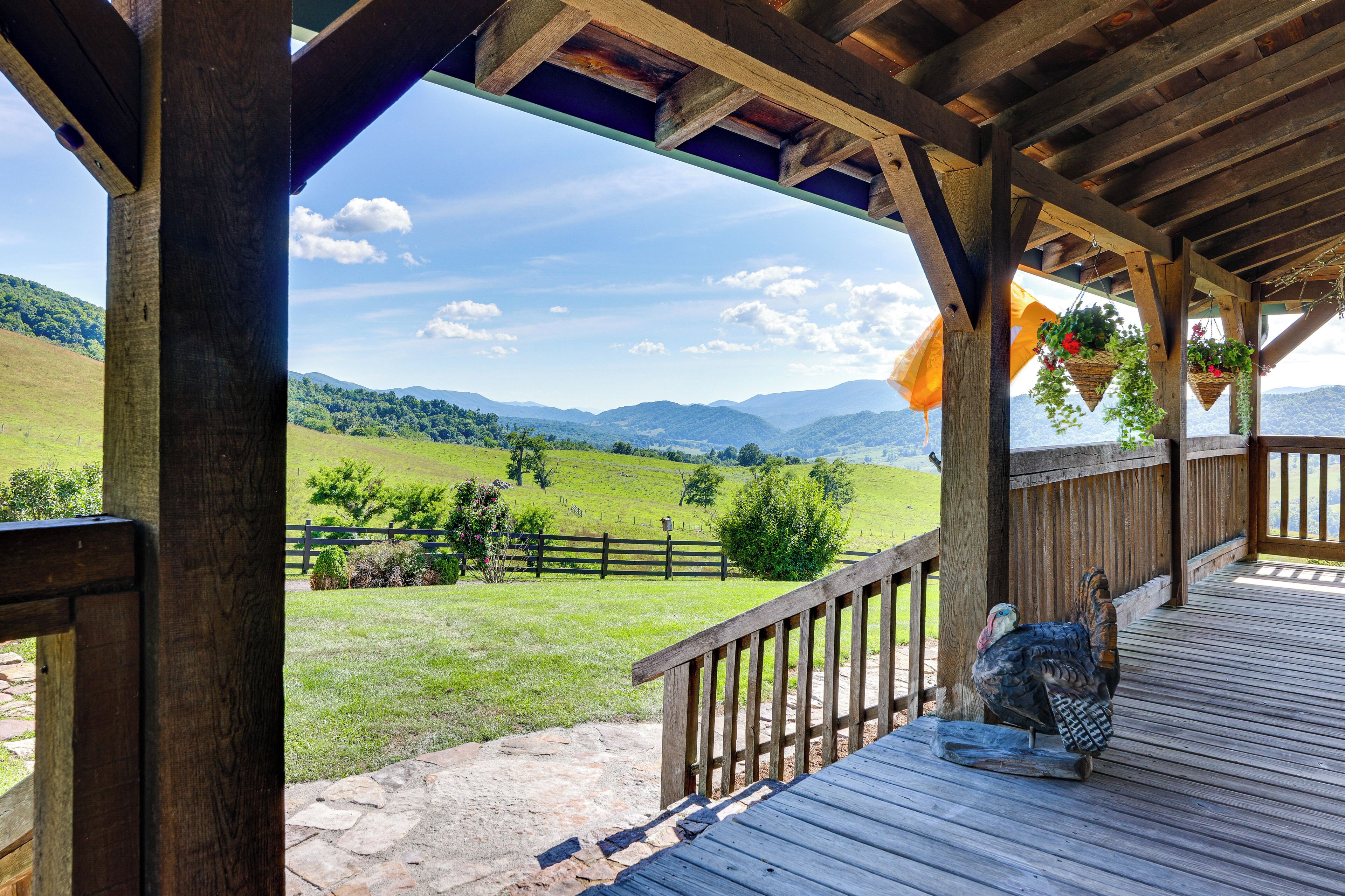 A wooden deck with a view of a green landscape and mountains.
