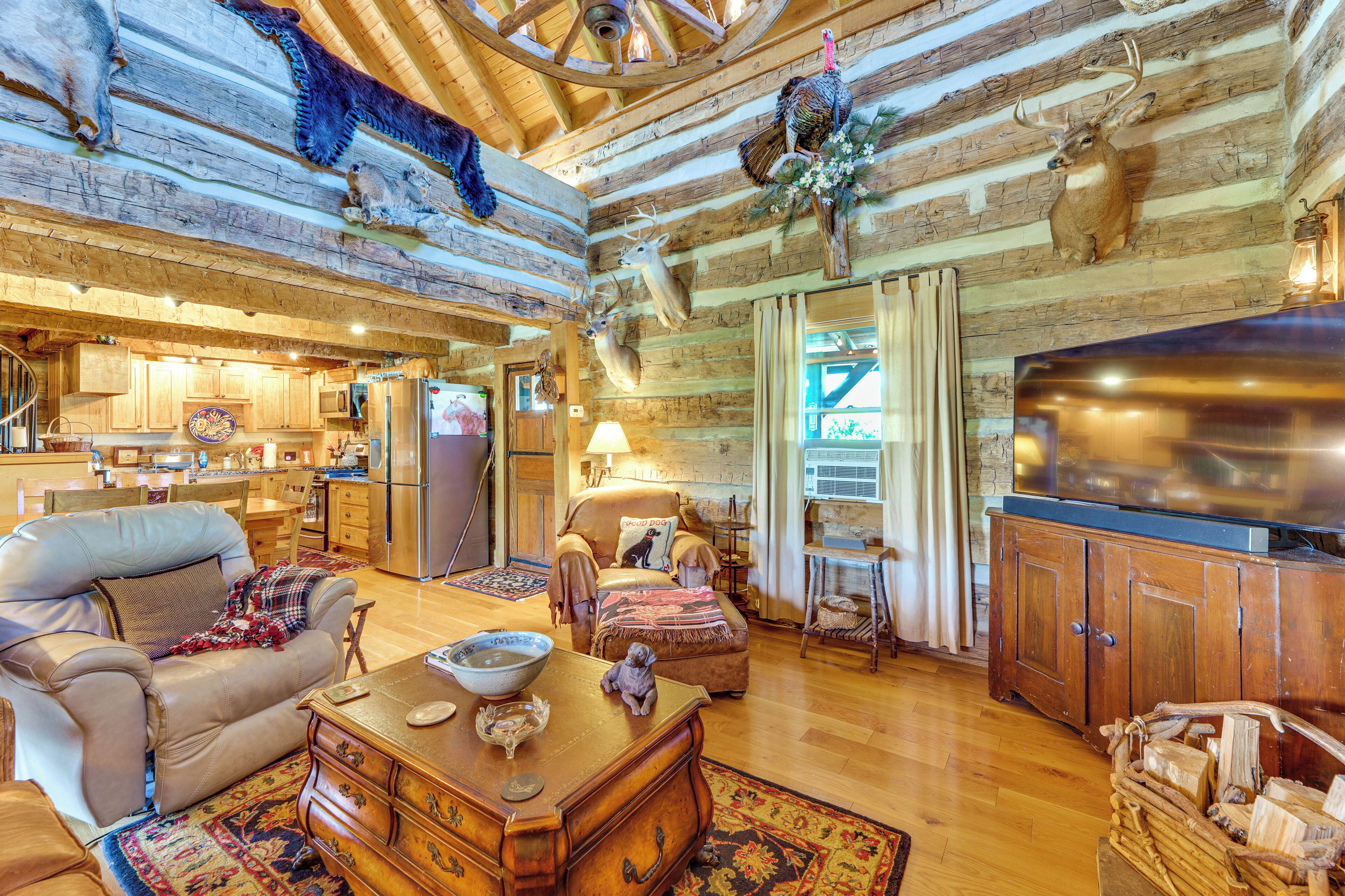 A rustic interior with a wooden ceiling, a kitchen area, a seating area with a leather sofa, and a television.