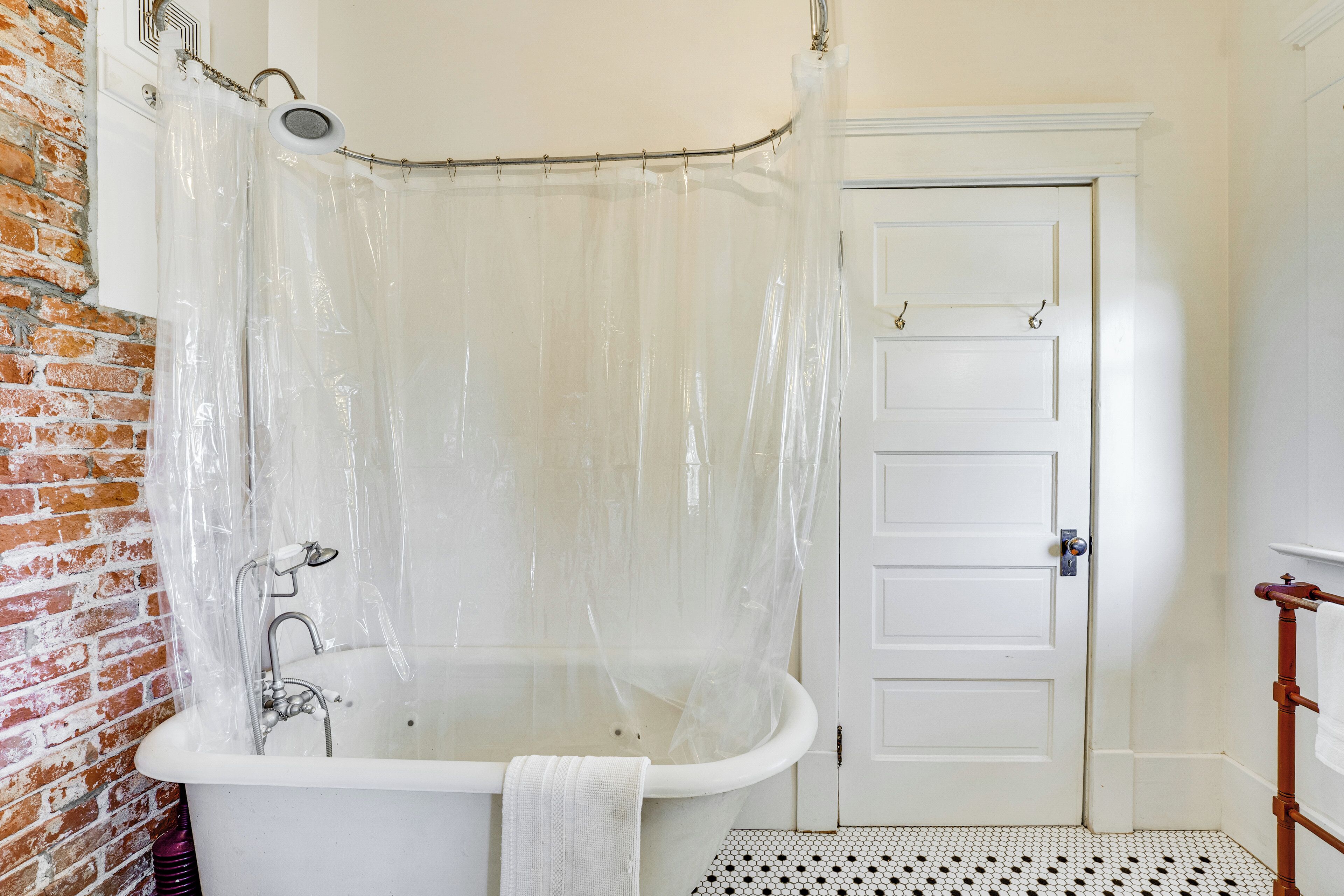 Ein Badezimmer mit einer weißen Badewanne, einer Duschvorhang, einer weißen Tür und einem gefliesten Boden.