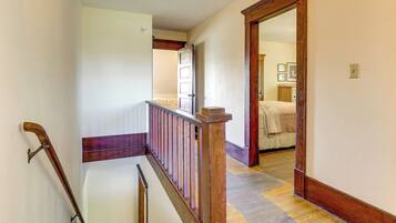 A hallway with a wooden handrail, a door leading to a bedroom, and a patterned carpet.