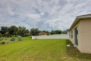 A residential property with a well-maintained lawn, a white fence, and a house with a flat roof. - Gateway to Disney! Home w/ Fenced Yard & Office (Mascotte)