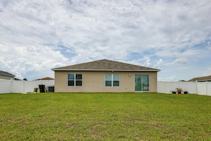 A single-story house with a flat roof, two windows, and a sliding glass door. - Gateway to Disney! Home w/ Fenced Yard & Office (Mascotte)