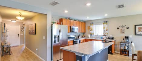 Una cocina moderna con una isla central, armarios de madera y un microondas empotrado.