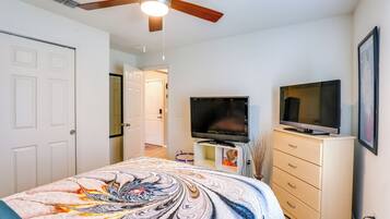 A bedroom with a bed, a TV, a dresser, and a ceiling fan.