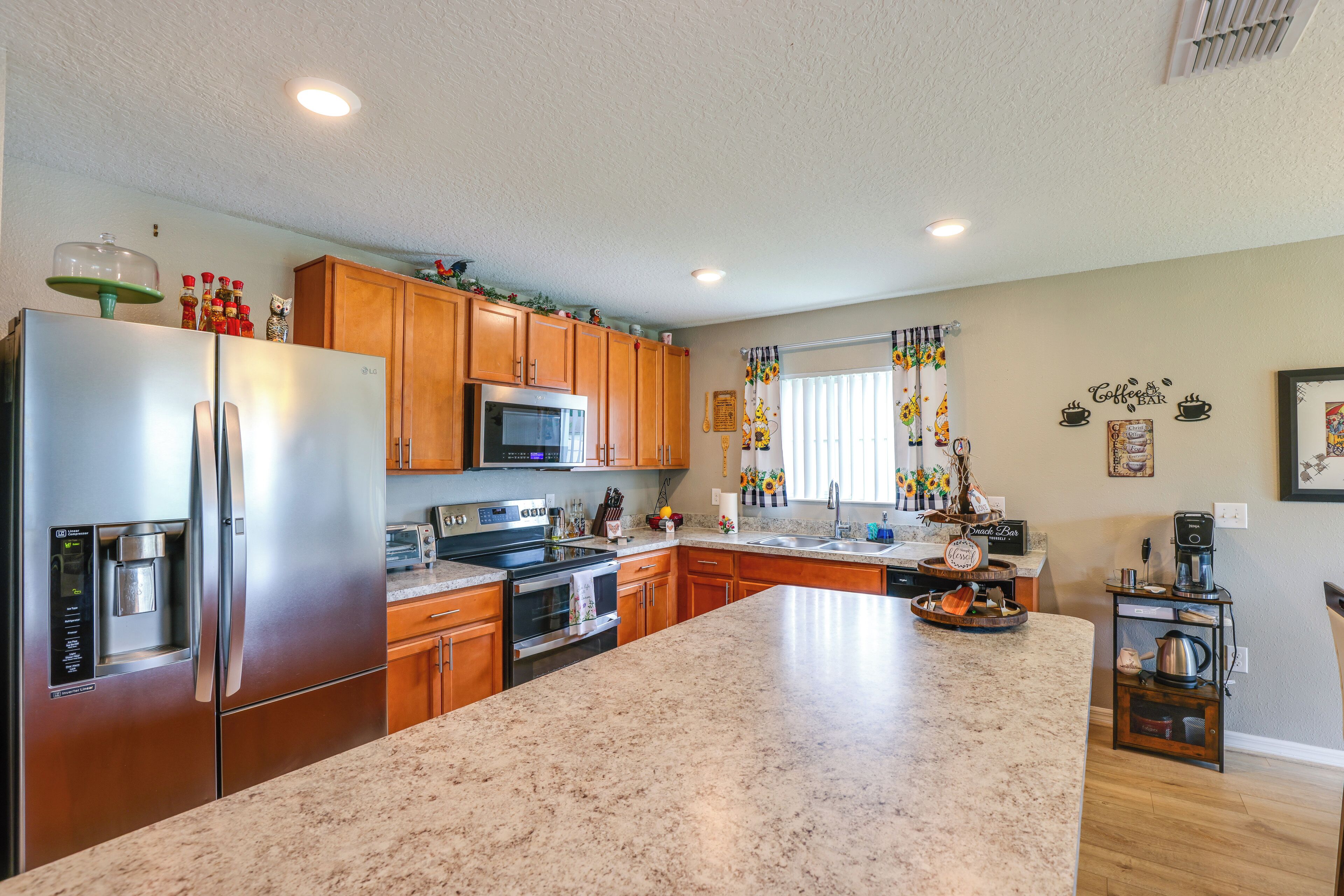 A modern kitchen with stainless steel appliances, wooden cabinets, and a granite countertop.
