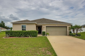A single-story house with a garage, a front lawn, and a well-maintained hedge. - Gateway to Disney! Home w/ Fenced Yard & Office (Mascotte)