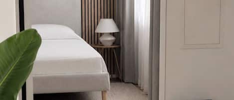 A bedroom with a bed, bedside table, lamp, and a radiator.