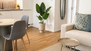 Una sala de estar moderna con un sofá, una mesa de centro y una zona de comedor con sillas y una planta.