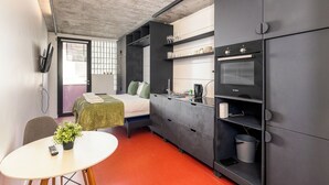 A compact room with a bed, kitchenette, and a small dining area. - The Urban Nest by CTHA (Cape Town)