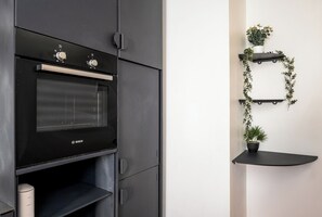 A kitchen with a Bosch oven, a black cabinet, and a wall-mounted plant shelf. - The Urban Nest by CTHA (Cape Town)