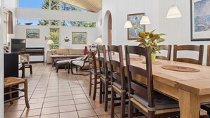 A spacious dining area with a wooden table and chairs, a television, and artwork on the walls. - Large holiday home with swimming pool (Tisvildeleje)