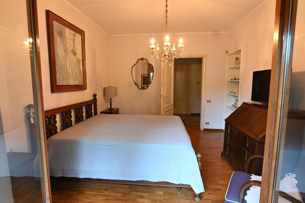 Quarto com cama, lustre, cômoda e televisão.